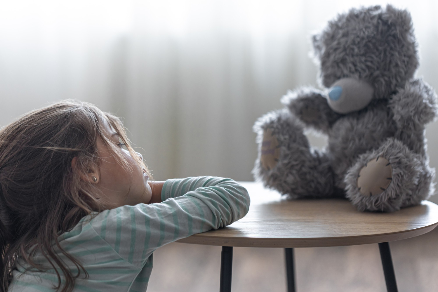 niña mirando un osito teddy