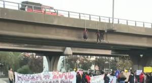 Personas cuelgan desde paso sobre nivel en Peñalolén