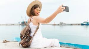 Mujer tomándose una selfie sentada en un muelle